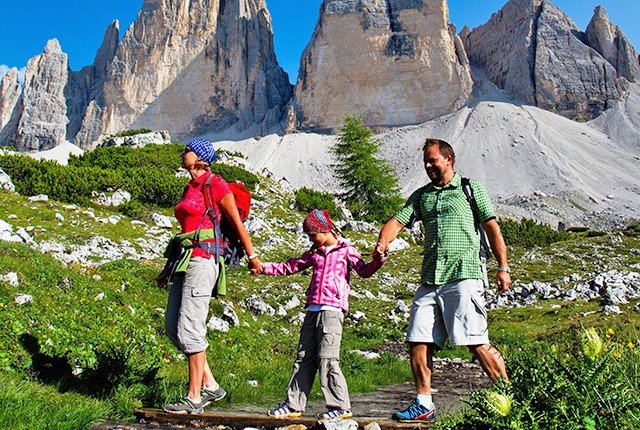 Family trekking in the Italian Alps during summer.